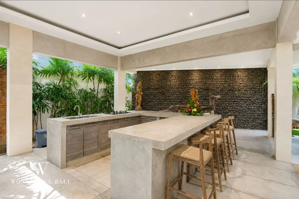 Outdoor kitchen with concrete L-bar and lava stone feature wall at villa in Seminyak, Bali