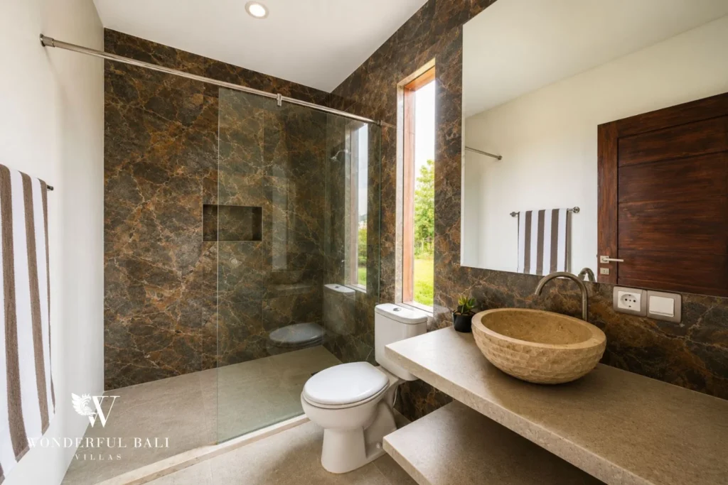 Bathroom with marble walls and walk-in shower in Nyanyi, Bali