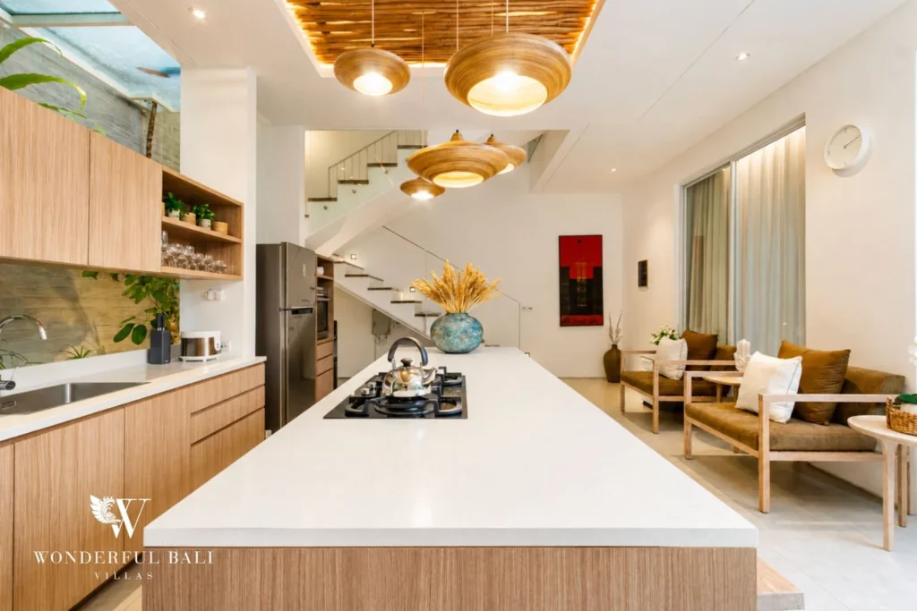 Large dining table with pendant lights and open kitchen at villa in Petitenget, Bali