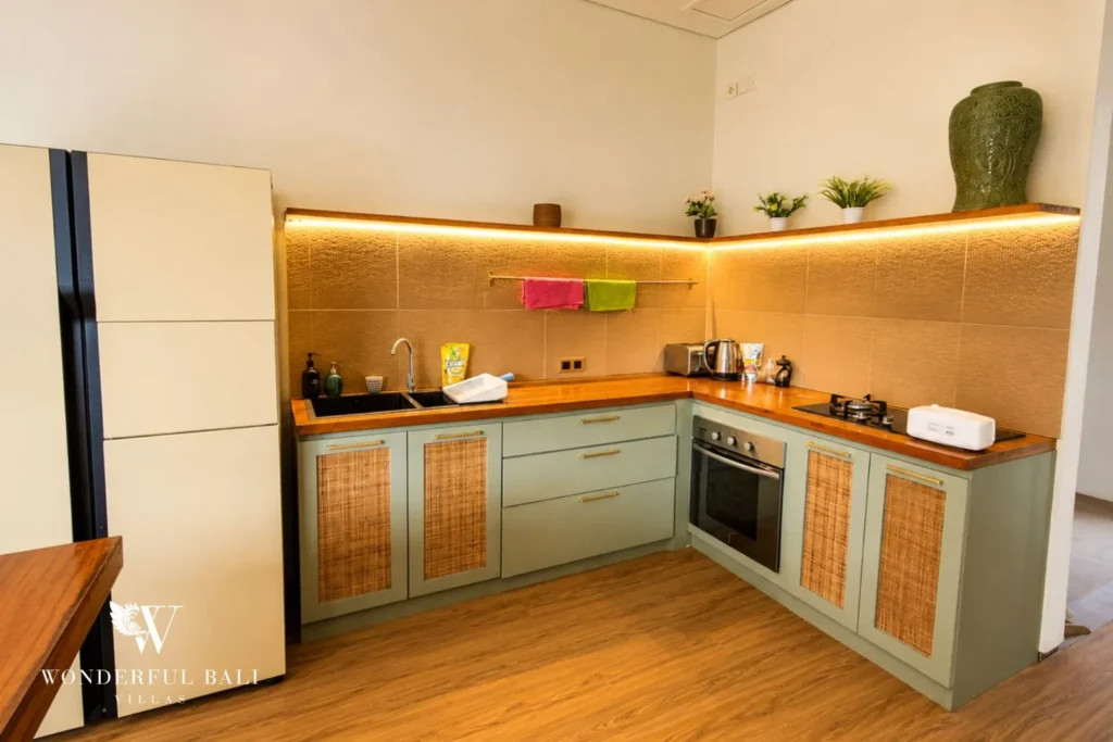 Modern kitchen with green cabinetry and timber counters at villa in Berawa, Bali
