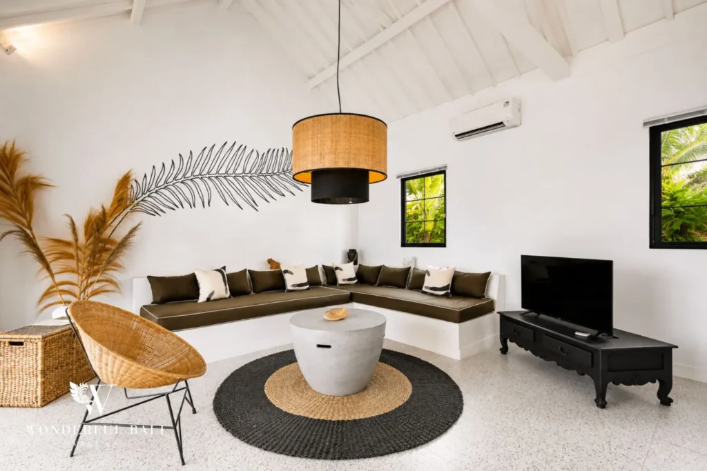 Living lounge with rattan chair, sofa and round rug at villa in Canggu, Bali