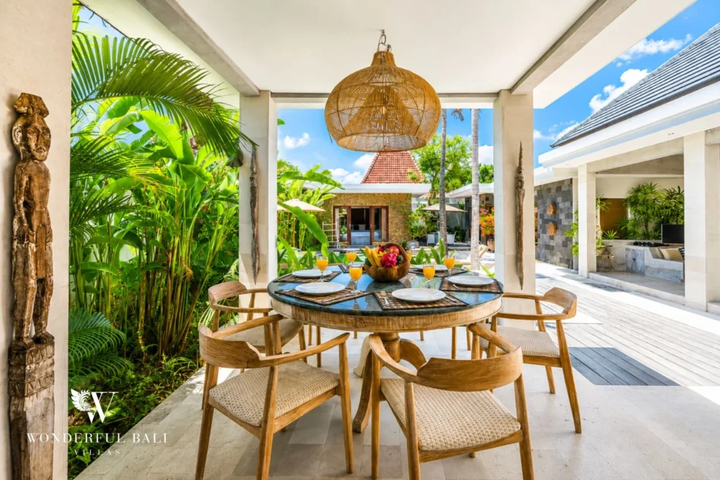 Outdoor dining table with rattan pendant and carved deity statue at villa in Seminyak, Bali