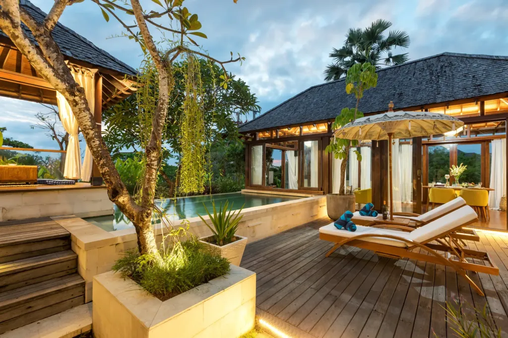Pool with lit thatched bale in the evening at villa in Batu Belig, Bali