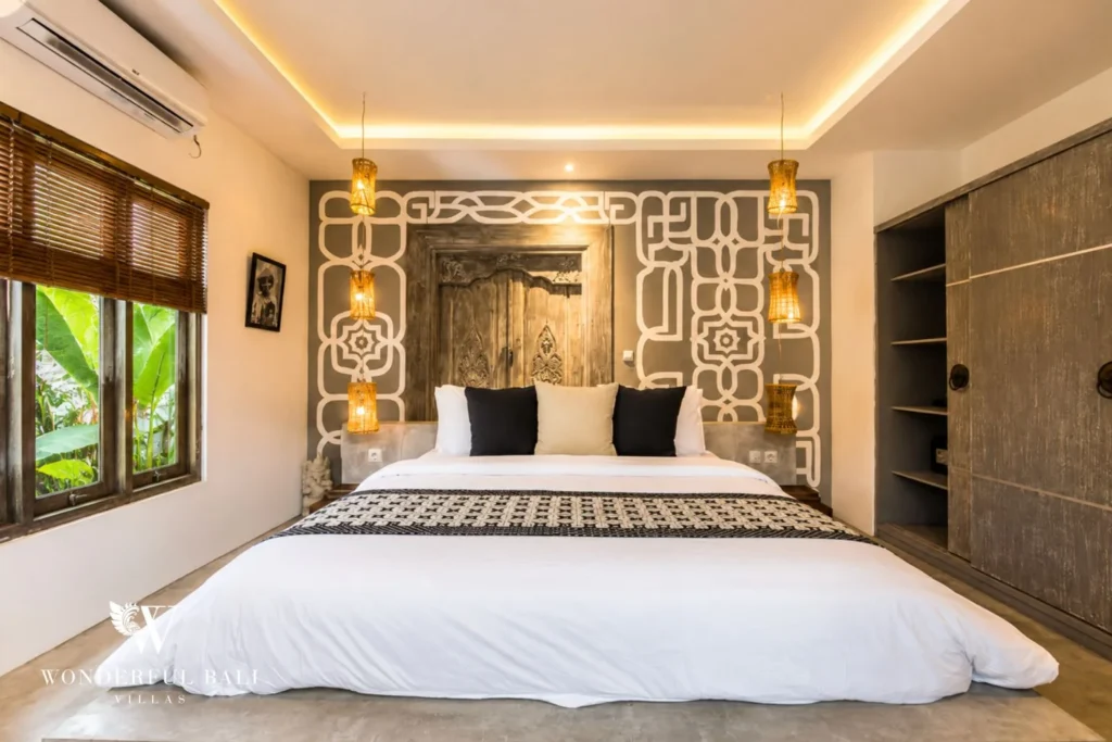 Bedroom with antique carved-door headboard and graphic feature wall at villa in Seminyak, Bali