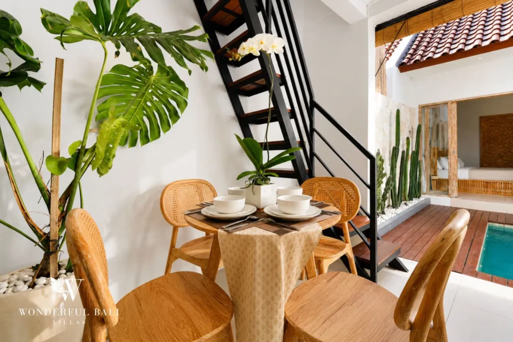 Dining nook with round table beside a staircase and plant at villa in Canggu, Bali