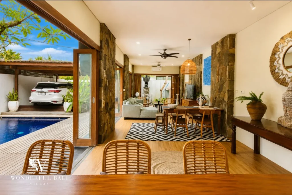 Living area with rattan chairs opening to the pool courtyard at villa in Berawa, Bali