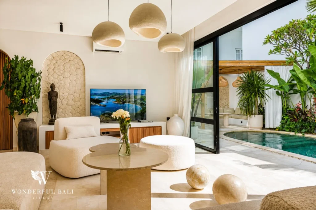Living area with curved sofa, TV and pool view at villa in Umalas, Bali