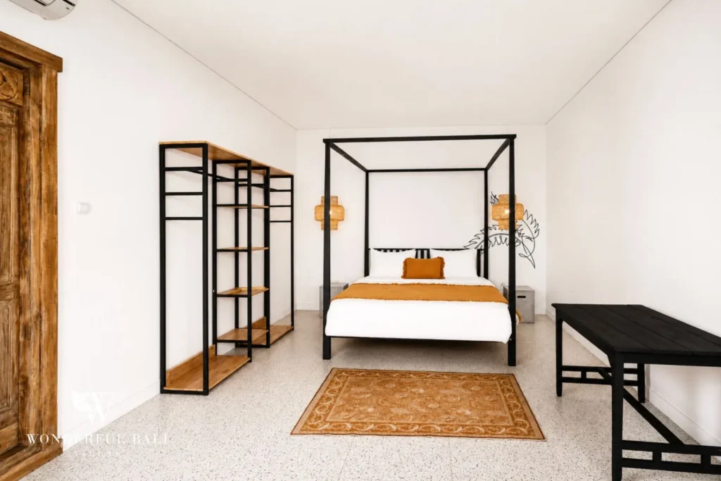 Bedroom with black four-poster bed and open wardrobe at villa in Canggu, Bali