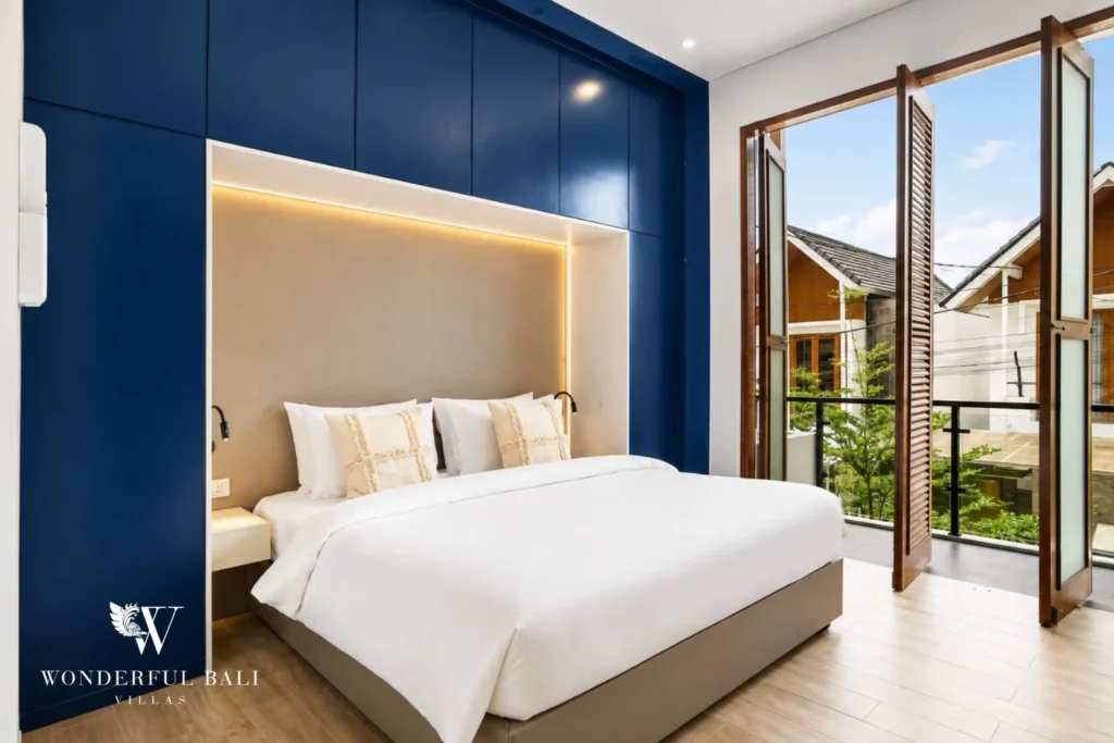Bedroom with blue feature wall and glass doors to a balcony at villa in Denpasar, Bali