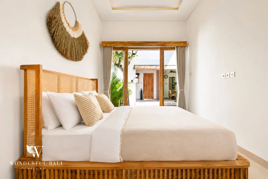 Bedroom with timber bed, woven wall decor and garden window at villa in Canggu, Bali