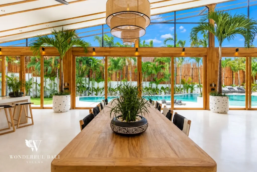Dining and kitchen with pool view through a glass wall at family villa in Umalas, Bali