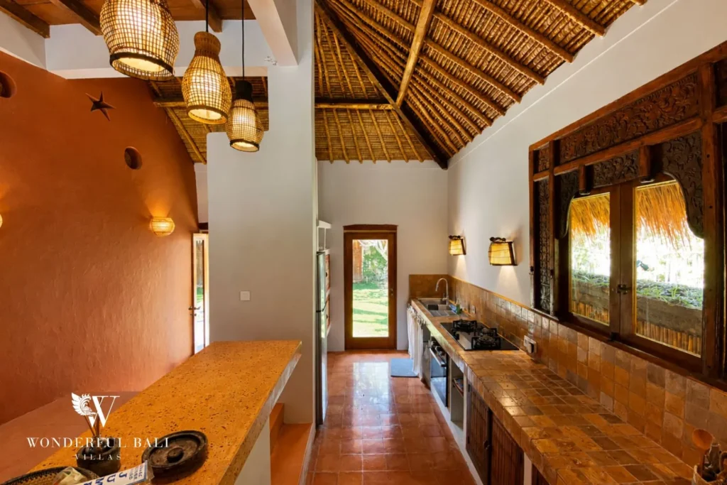 Kitchen with arched terracotta walls under a thatched roof at villa in Bumbak, Bali
