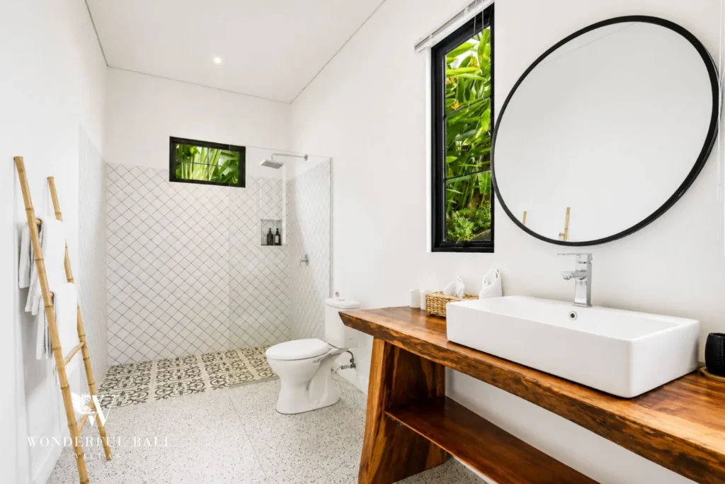 Bathroom with round mirror, vessel basin and walk-in shower at villa in Canggu, Bali