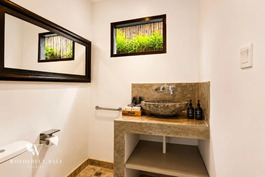 Bathroom with vessel basin and framed view to a green garden at villa in Umalas, Bali