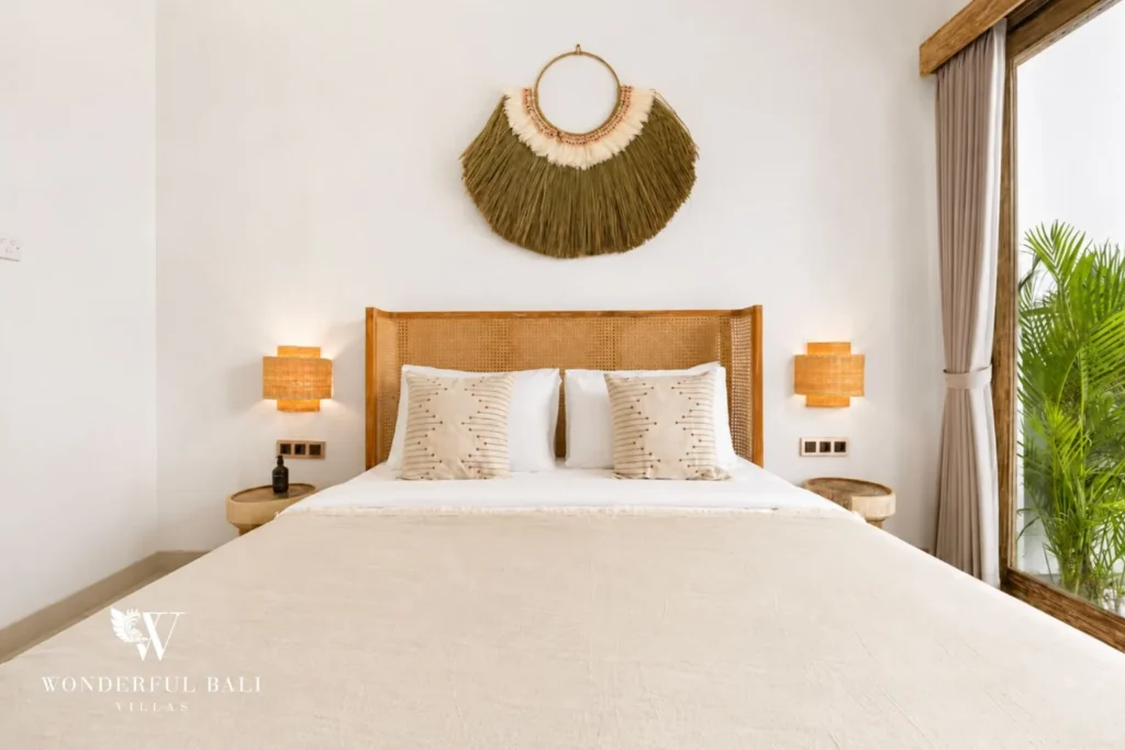Bedroom with woven sun decor, bedside lamps and garden doors at villa in Canggu, Bali