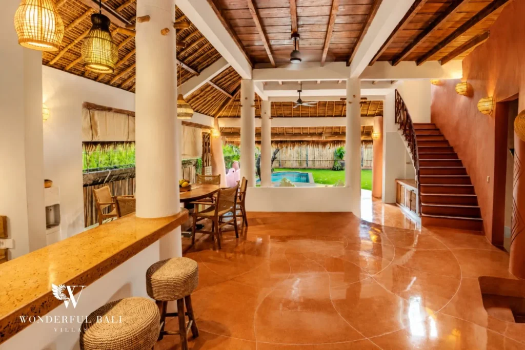 Open living and dining with terracotta floor and staircase at villa in Bumbak, Bali