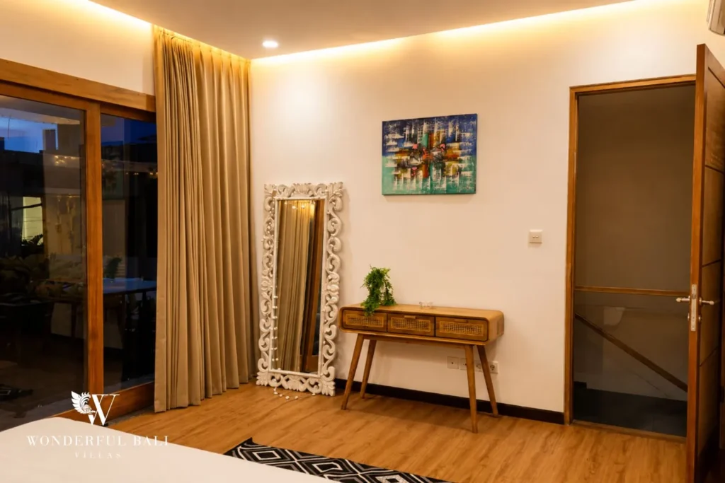 Bedroom with framed artwork, timber bench and ensuite access at villa in Berawa, Bali