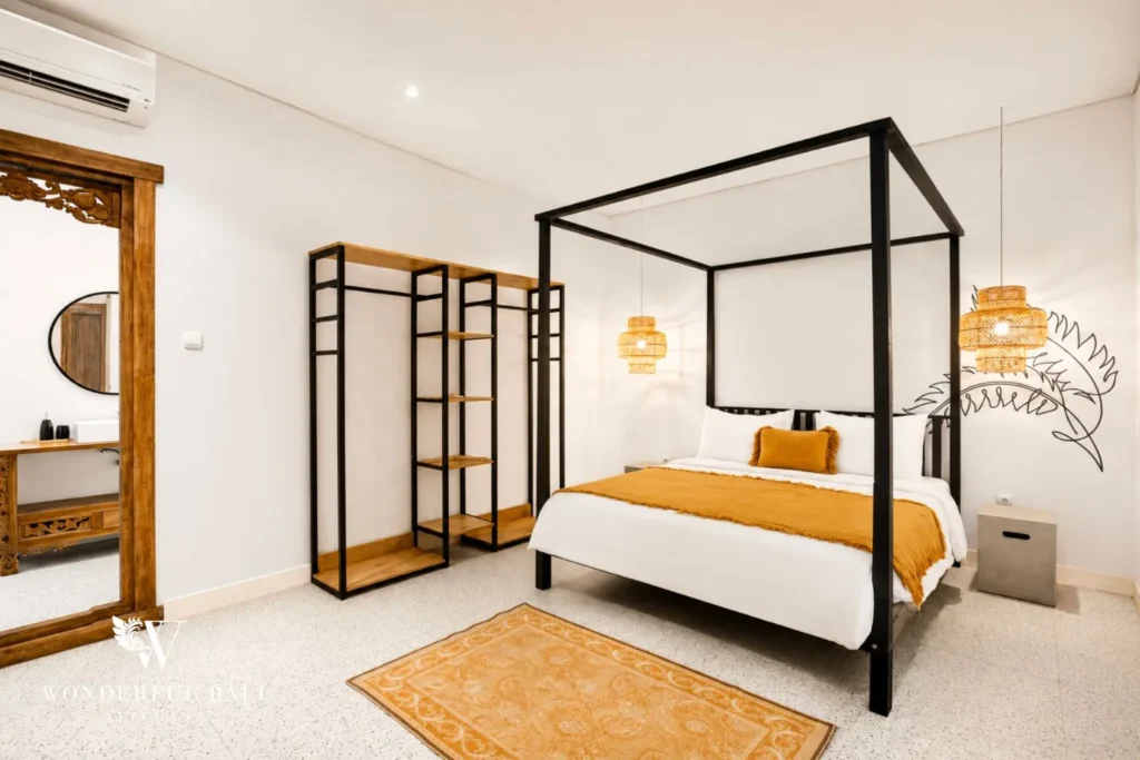 Bedroom with black four-poster bed and round mirror at villa in Canggu, Bali
