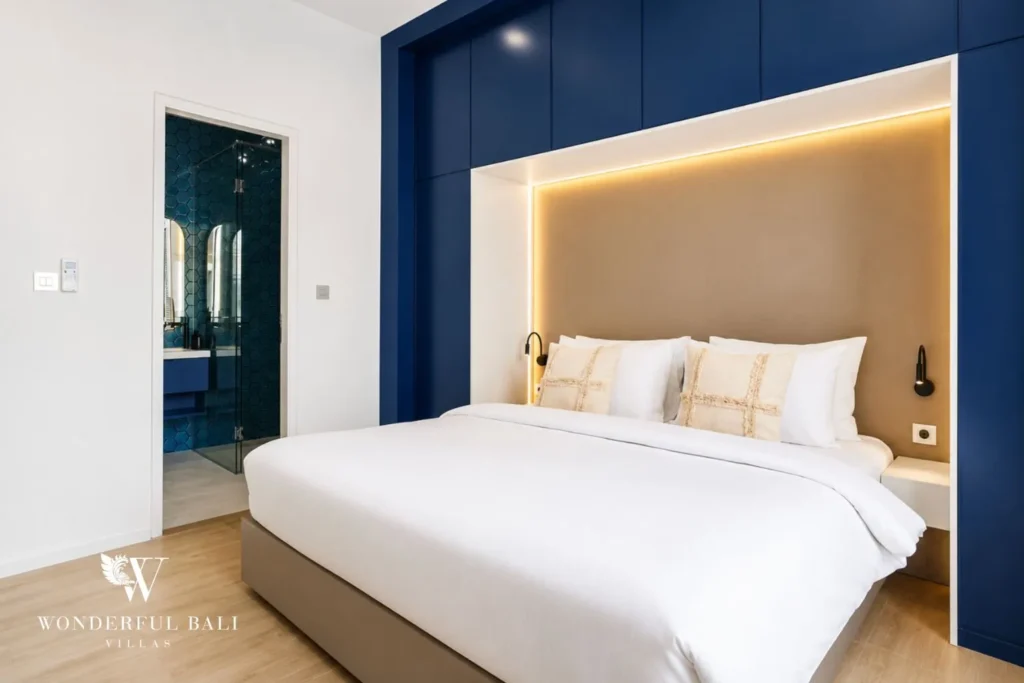 Bedroom with blue headboard wall and ensuite access at villa in Denpasar, Bali