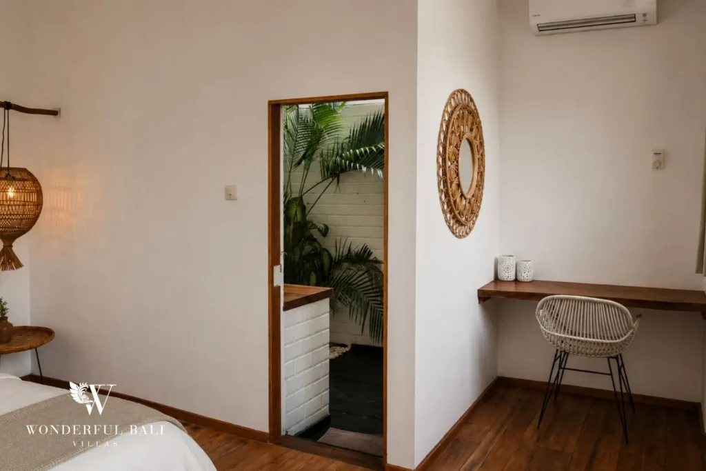 Bedroom with desk nook and round woven mirror at villa in Canggu, Bali