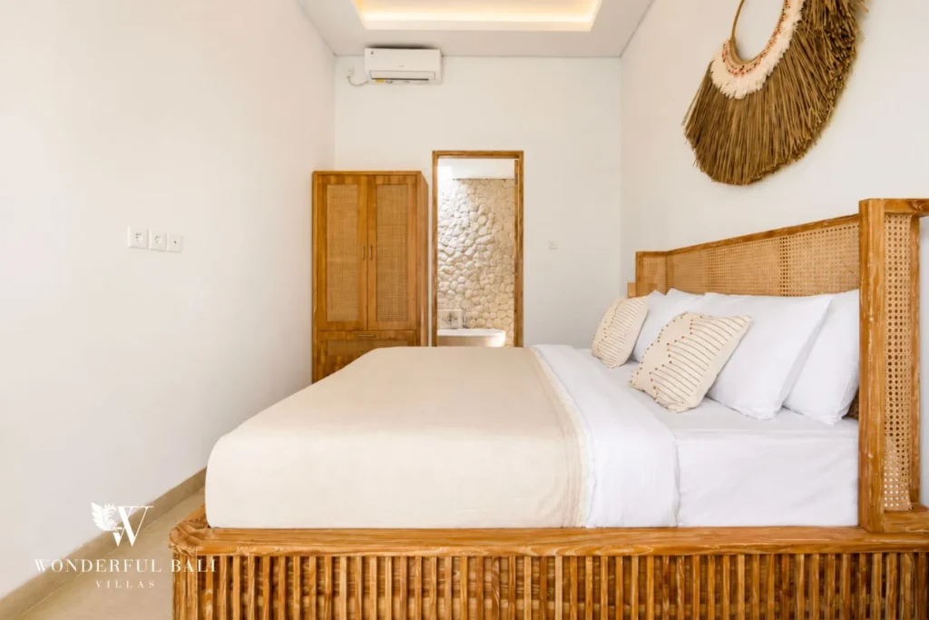 Bedroom with timber bed, woven fan decor and mirror at villa in Canggu, Bali