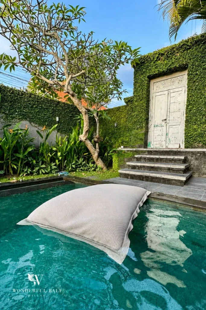 Poolside daybed surrounded by dense tropical garden at villa in Canggu, Bali
