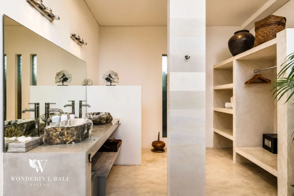 Bathroom with twin petrified-wood vessel basins and walk-in wardrobe at villa in Seminyak, Bali