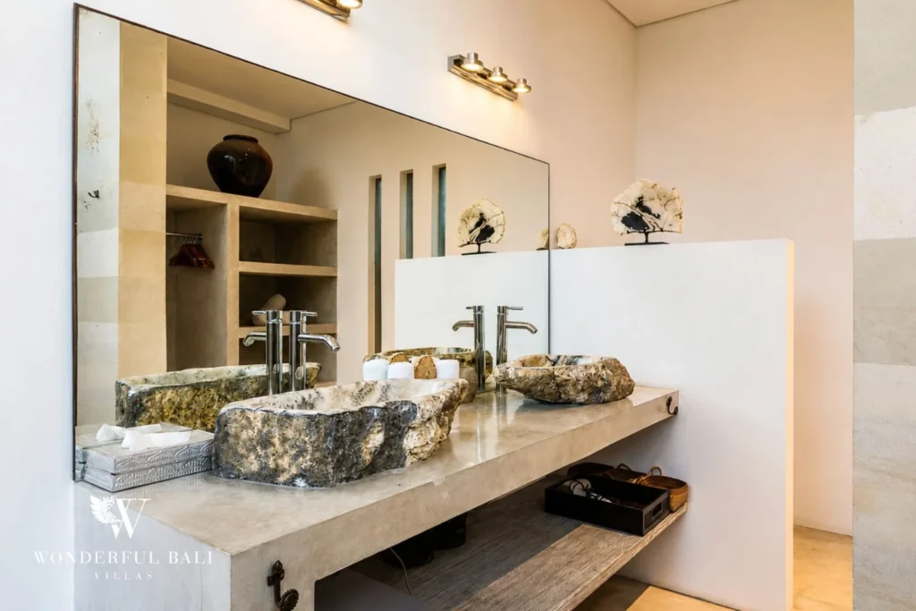 Bathroom detail with petrified-wood vessel basins on concrete counter at villa in Seminyak, Bali