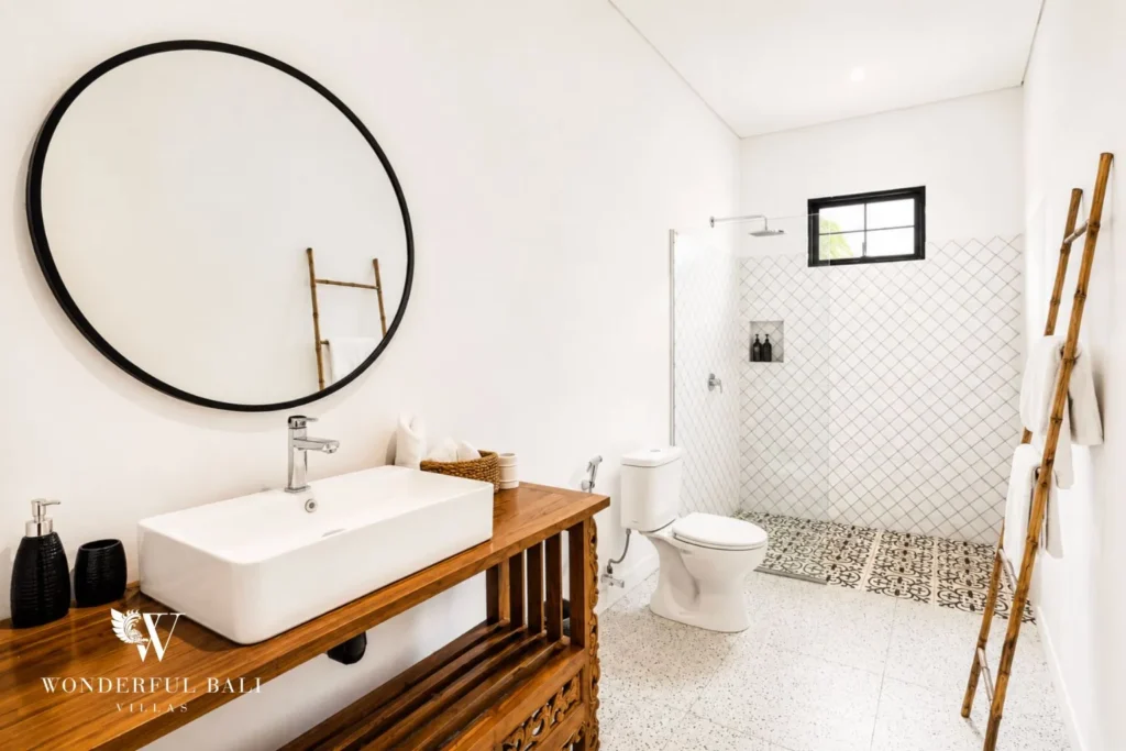 Bathroom with round mirror, vessel basin and timber vanity at villa in Canggu, Bali