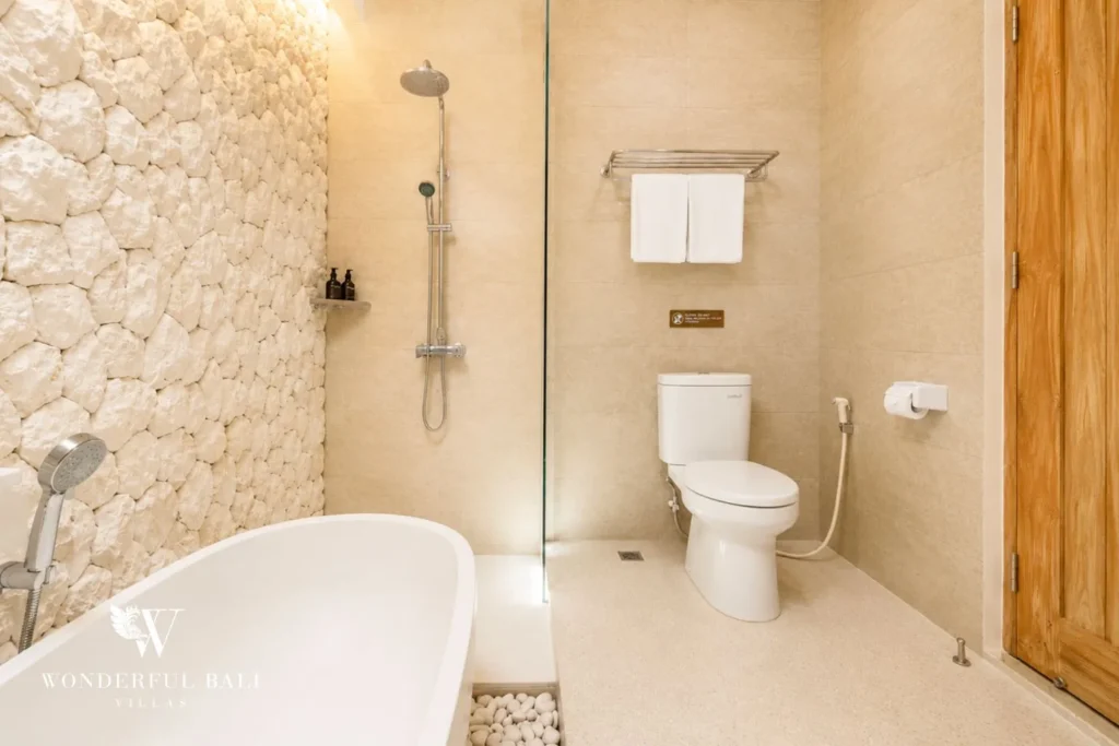 Bathroom with stone wall, walk-in shower and freestanding tub at villa in Canggu, Bali