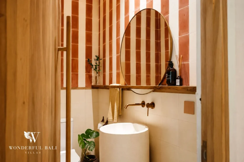 Bathroom with striped wall, vessel basin and terrazzo finish at villa in Berawa, Bali