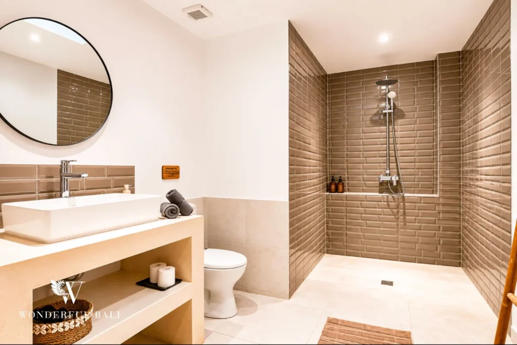 En-suite bathroom with walk-in shower and round mirror at villa in Umalas, Bali