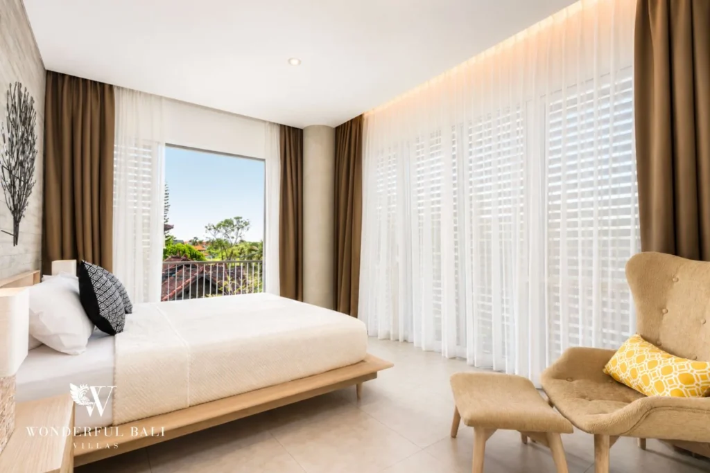 Bright bedroom with king bed and armchair at villa in Petitenget, Bali