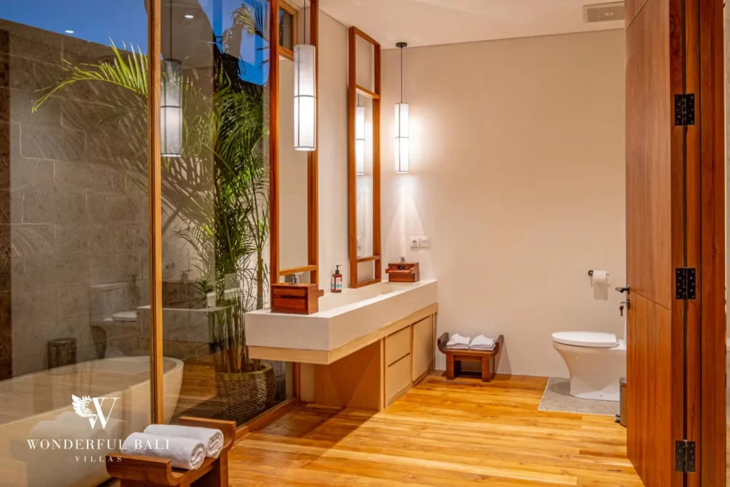 Bedroom with glass walls and timber finishes opening to a view at villa in Umalas, Bali