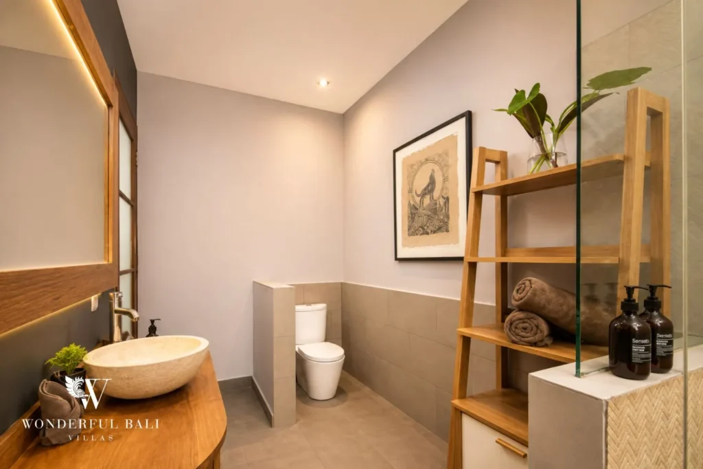 Bathroom with vessel basin, framed art and open shelving at villa in Umalas, Bali