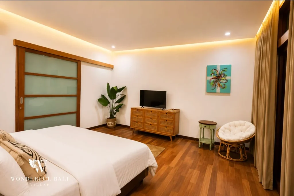 Bedroom with white bed, green panel detailing and wall-mounted TV at villa in Berawa, Bali
