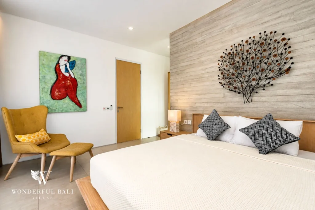 Bedroom with king bed, stone feature wall and artwork at villa in Petitenget, Bali