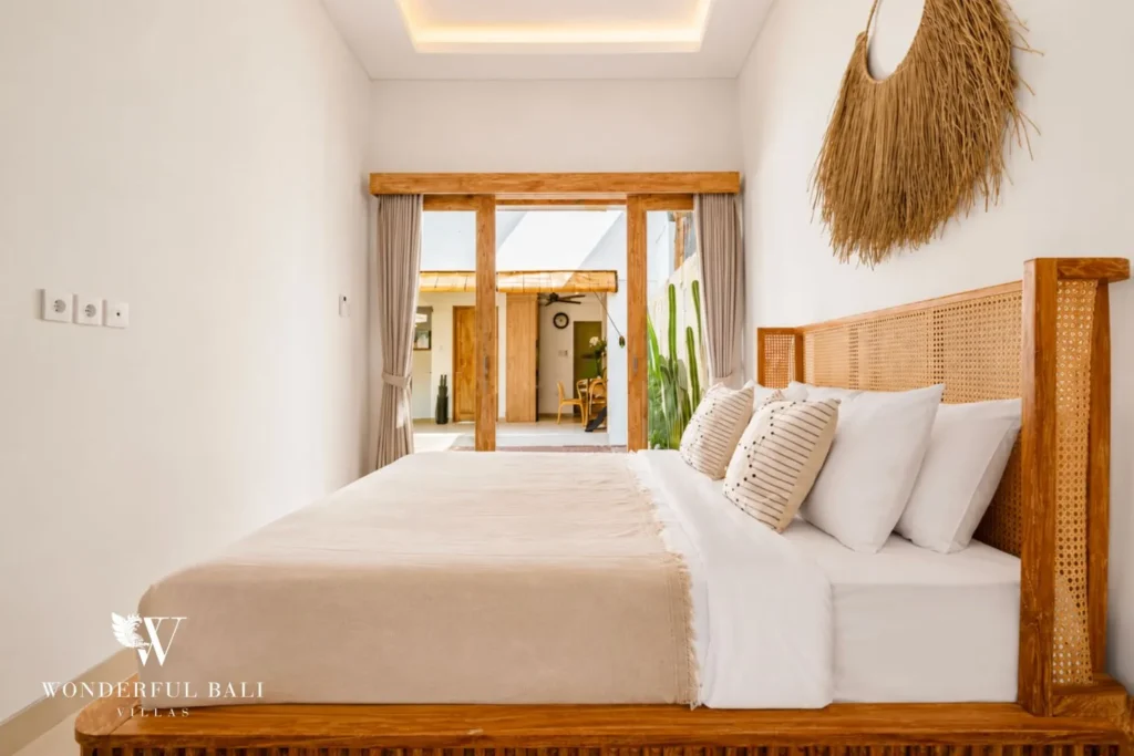 Bedroom with timber bed, white linens and garden window at villa in Canggu, Bali