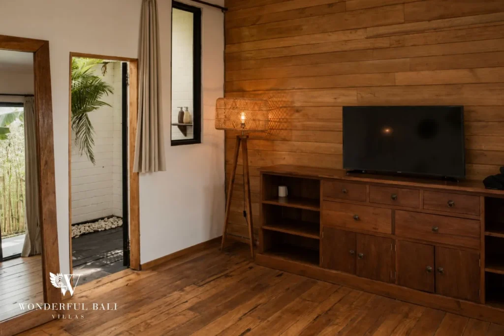 Bedroom with wall TV, timber feature wall and console at villa in Canggu, Bali