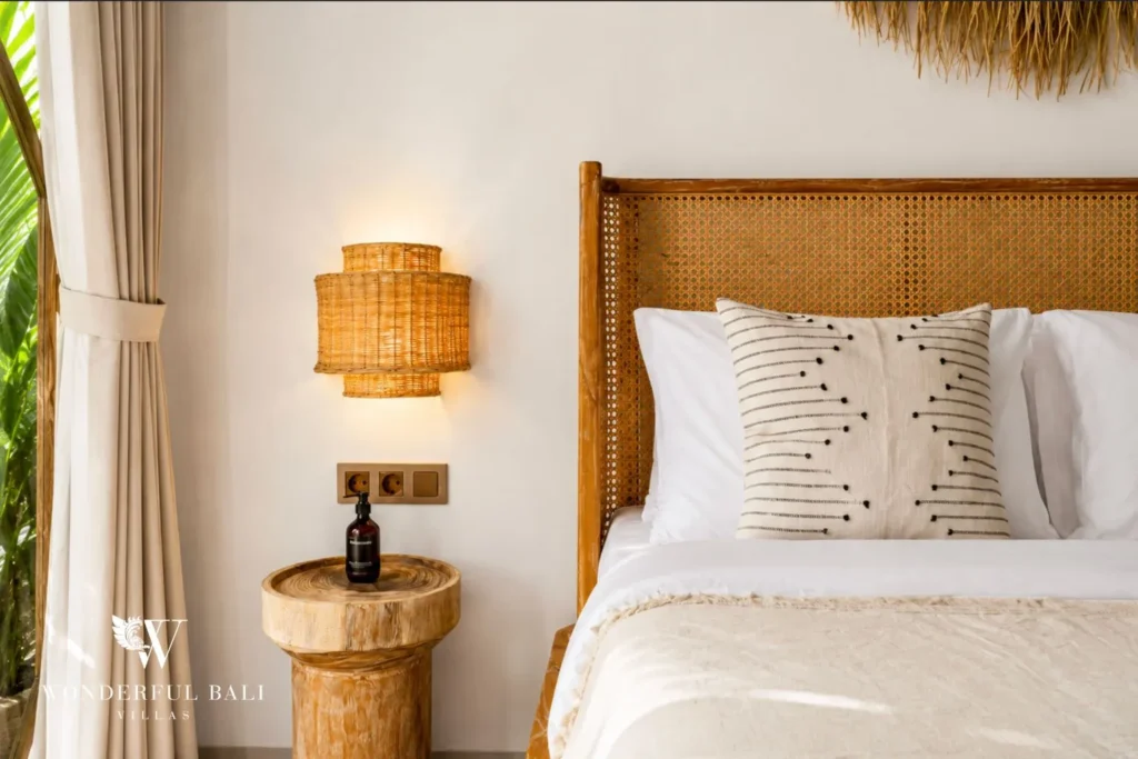 Bedroom with rattan lamp, timber headboard and white bed at villa in Canggu, Bali