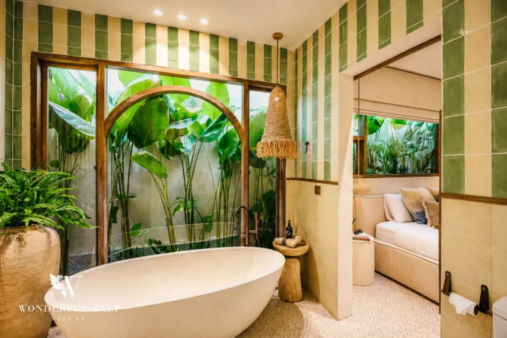 Bathroom with green-striped walls and freestanding tub by an arched window at villa in Berawa, Bali