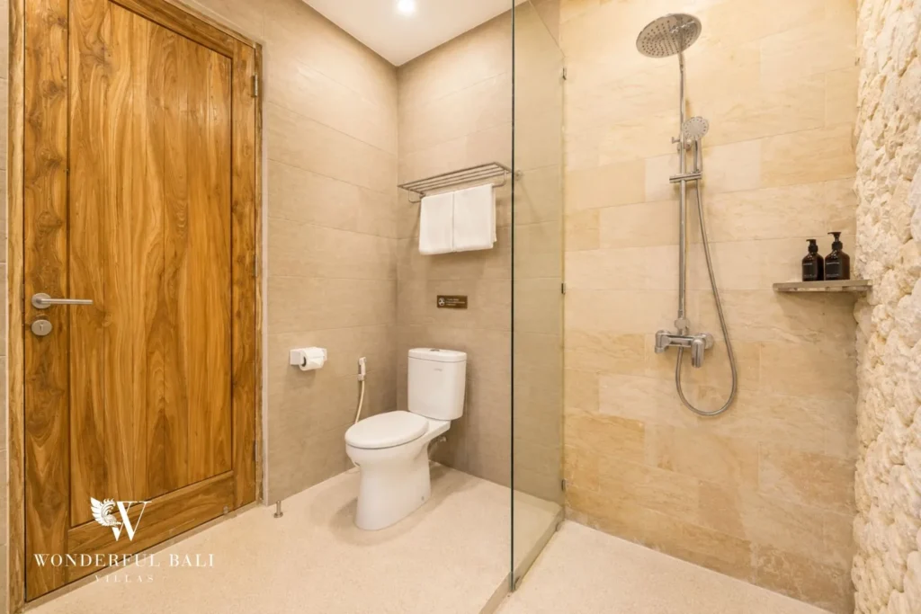 Bathroom with timber door, walk-in shower and stone finish at villa in Canggu, Bali