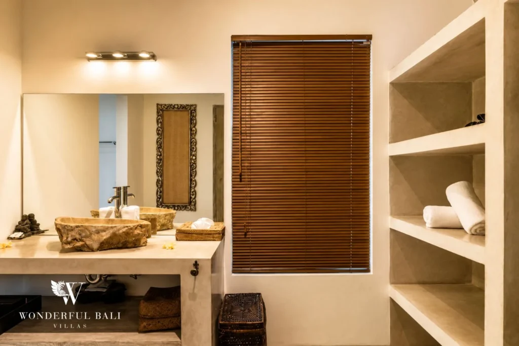 Bathroom with travertine vessel basin and timber blinds at villa in Seminyak, Bali
