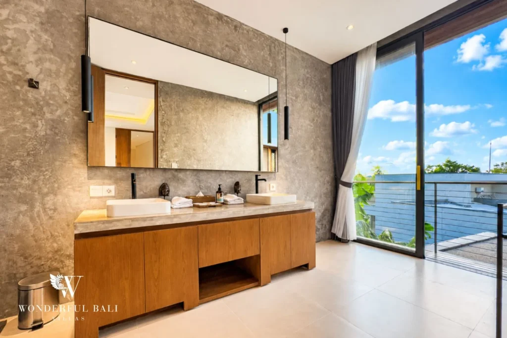 Bedroom with bed and garden view through glass at villa in Umalas, Bali
