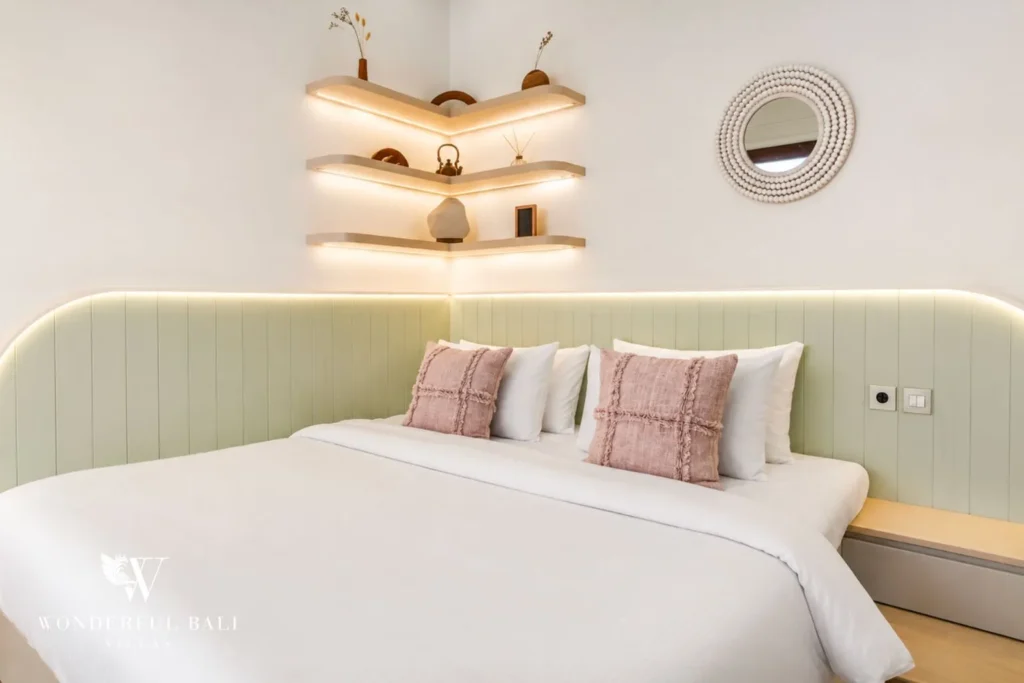 Bedroom with green headboard, pink cushions and shelving at villa in Denpasar, Bali