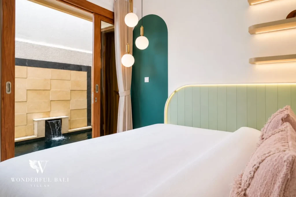 Bedroom with green accent, pink throw and pendant lights at villa in Denpasar, Bali