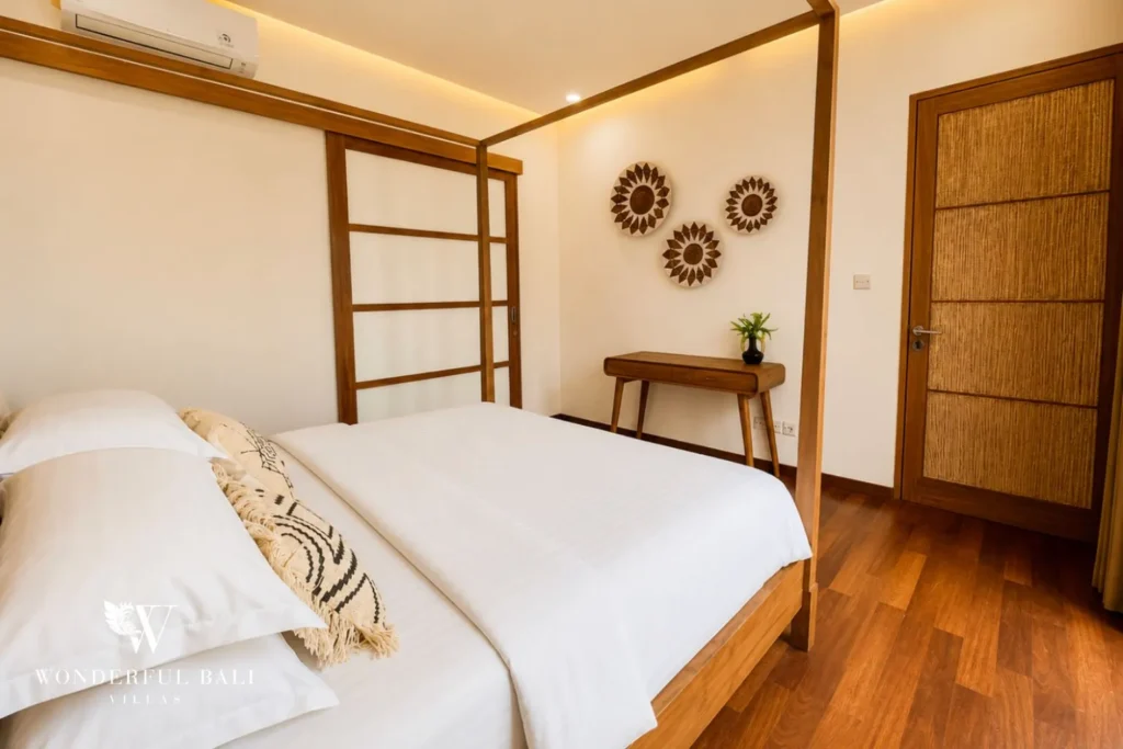 Bedroom with timber canopy bed and woven wall decor at villa in Berawa, Bali