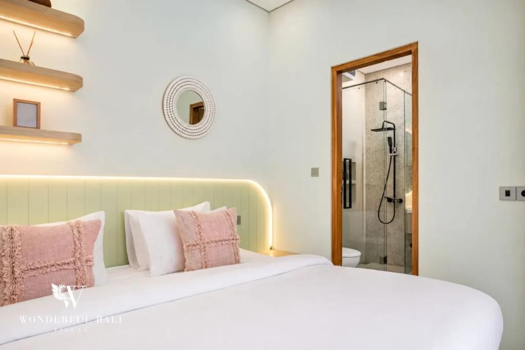 Bedroom with green headboard, shelving and ensuite access at villa in Denpasar, Bali