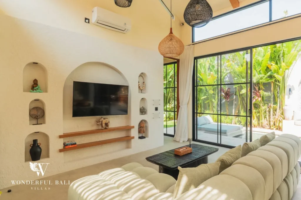 Living area with TV, glass doors and plants at villa in Seseh, Bali