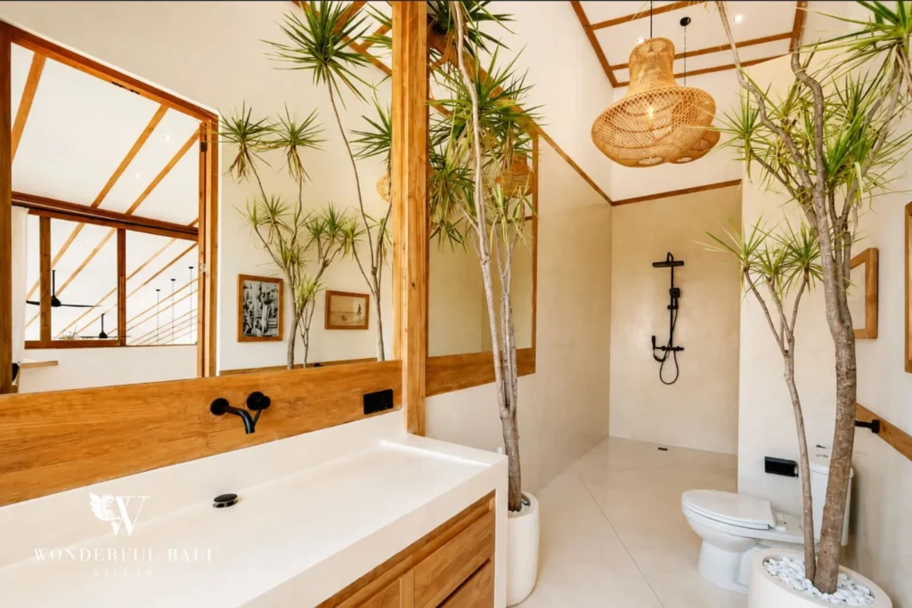 Freestanding bathtub among tropical plants and natural light at family villa in Umalas, Bali